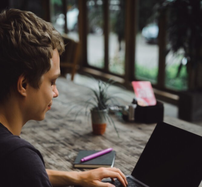 A man sitting at a table with a laptop, working on coding at Acceleratron in Pune and Kolkata.